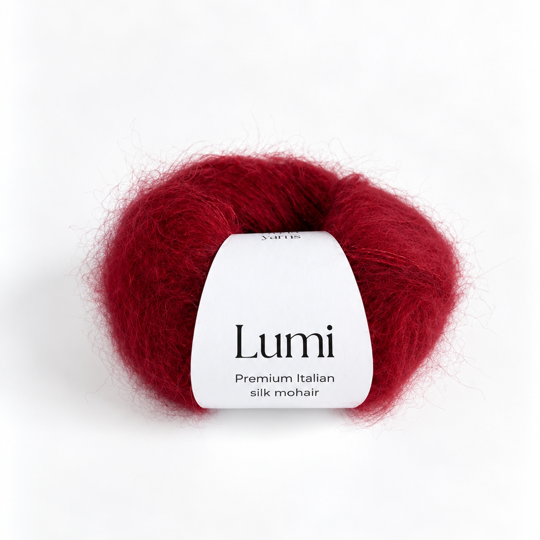 A ball of Lumi Premium Italian Silk Mohair yarn in a deep crimson red color, featuring a white paper label in the center, set against a clean white background.