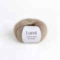 A ball of Lumi Premium Italian silk mohair yarn in a light beige color, featuring a white paper label with black text, set against a seamless white background.