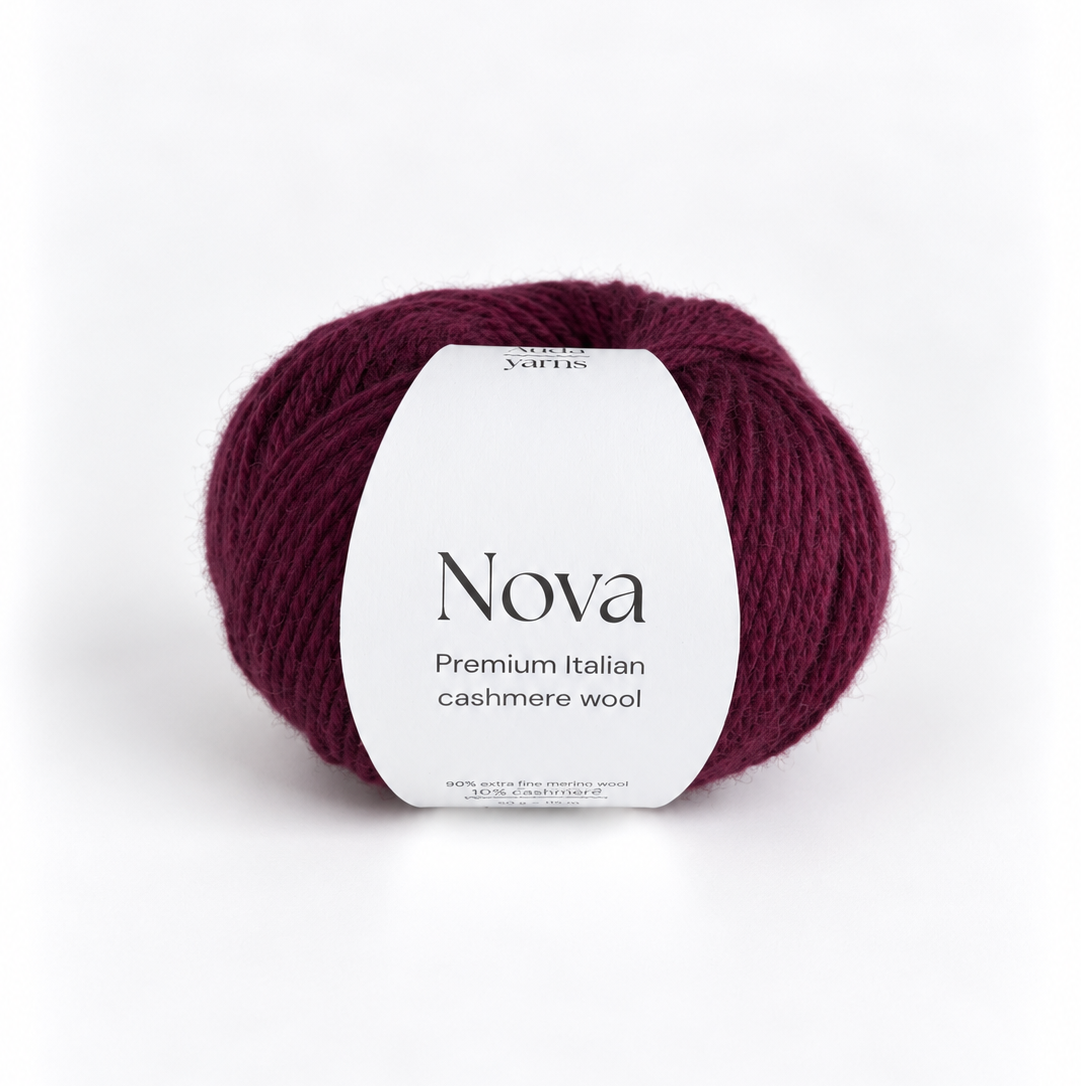 A ball of Nova Premium Italian Cashmere Wool yarn in a deep burgundy color, featuring a white paper label with black text, set against a clean white background.