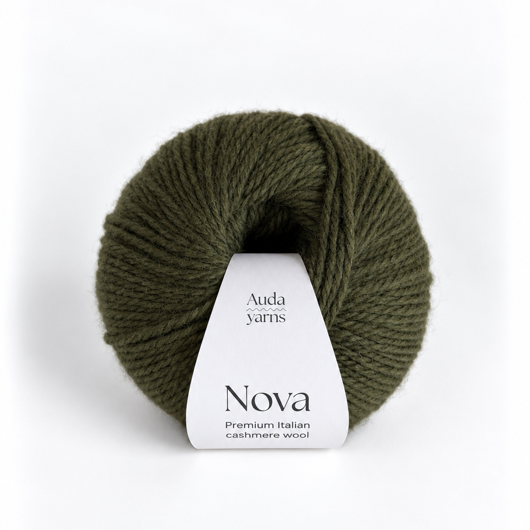 A skein of olive green yarn with a white paper label that reads 'Auda Yarns Nova Premium Italian cashmere wool' on a clean white background.