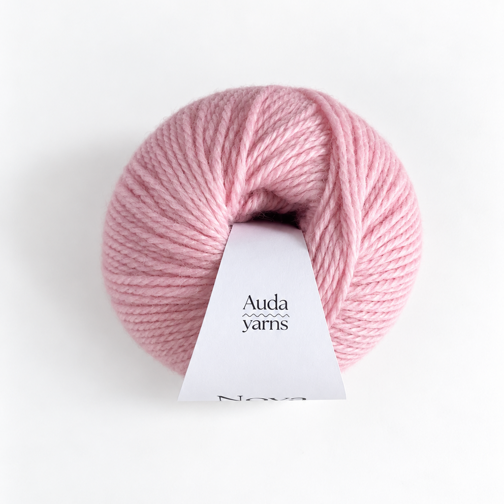 A pink ball of yarn with a white paper label that reads 'Auda yarns' and 'Nova', photographed on a clean white background.