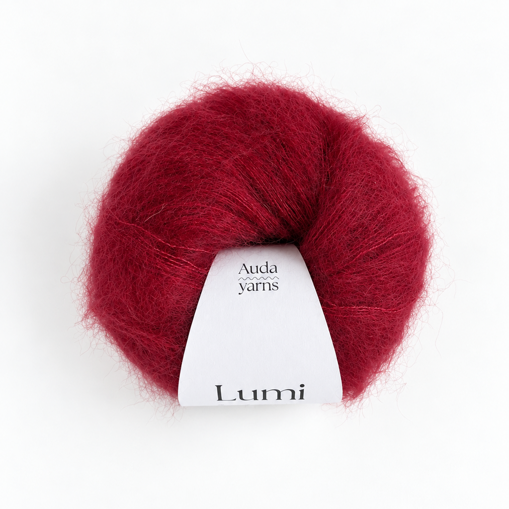 A ball of deep burgundy red yarn with a white paper label that reads 'Auda yarns Lumi', centered on a clean white background.