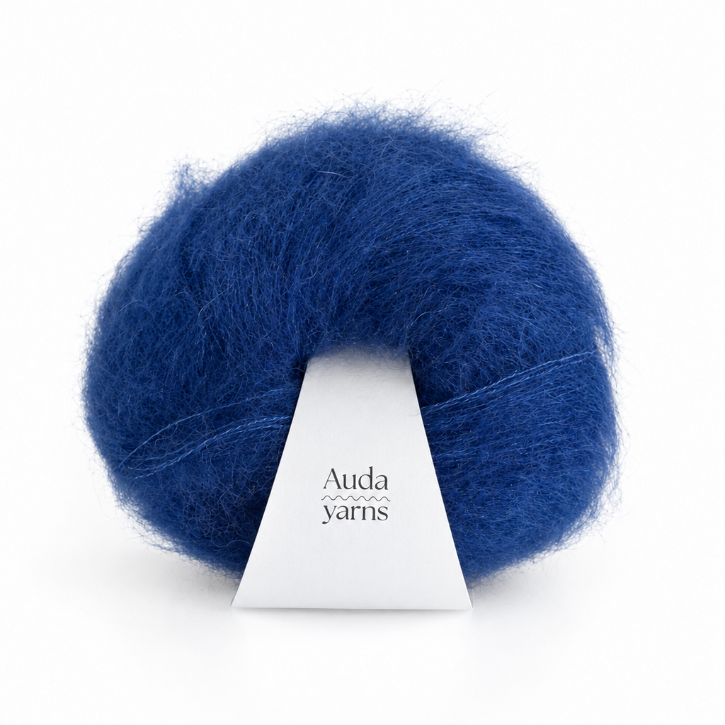 A ball of fluffy royal blue yarn with a white paper label that reads 'Auda yarns', set against a clean white background.